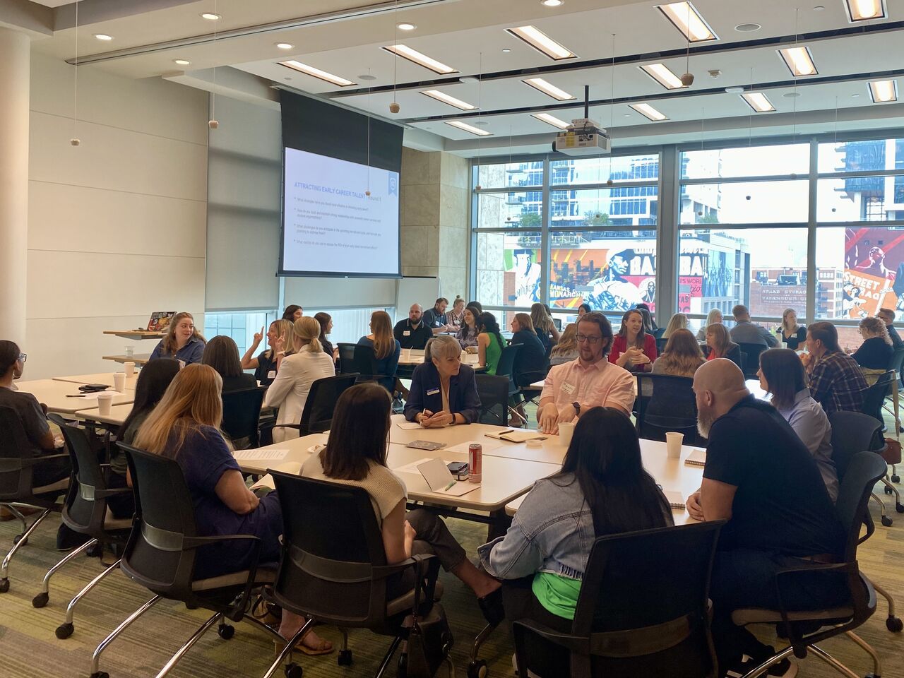 Room of talent professionals sitting around tables, talking