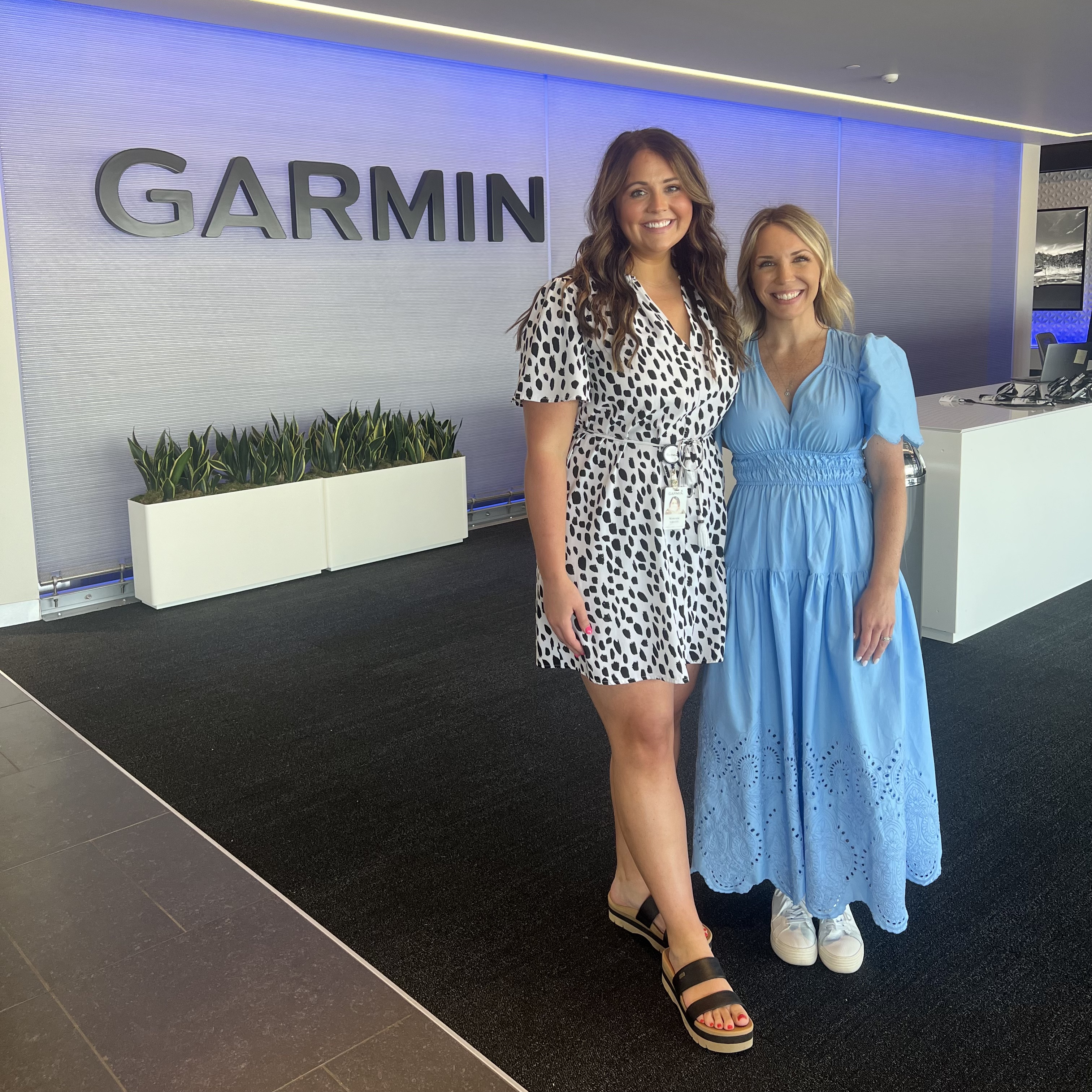 Danielle Hilton and Makenzie Kalkowski smile in front of Garmin lobby