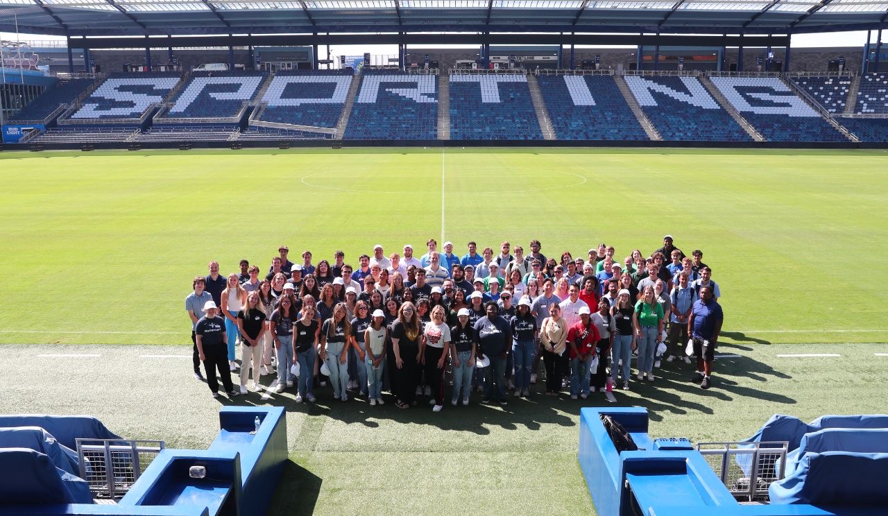 Group of 125 interns standing near the pitch at Children's Mercy Park.